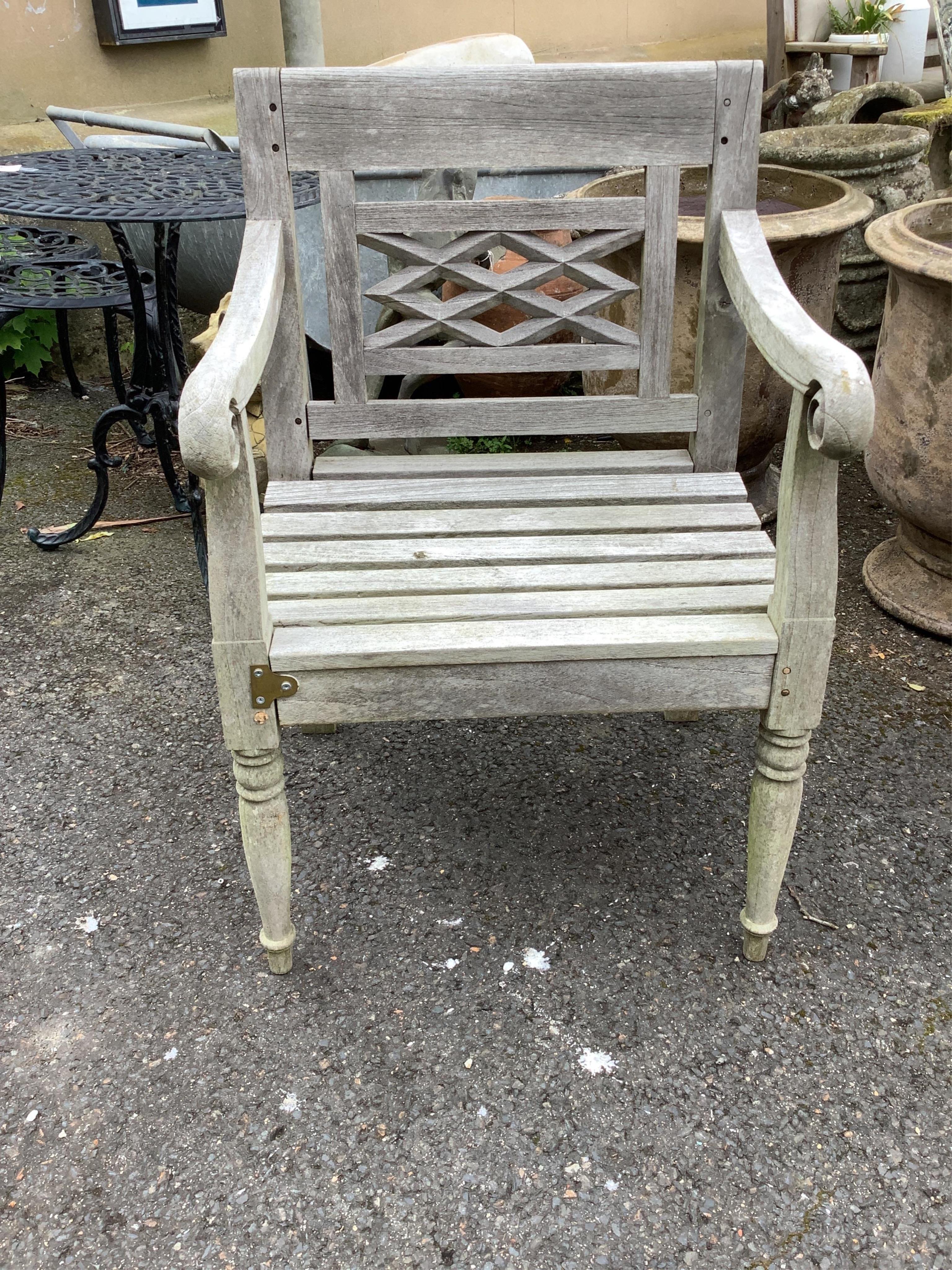 A circular weathered teak garden table, width diameter 150cm, height 73cm and four elbow chairs